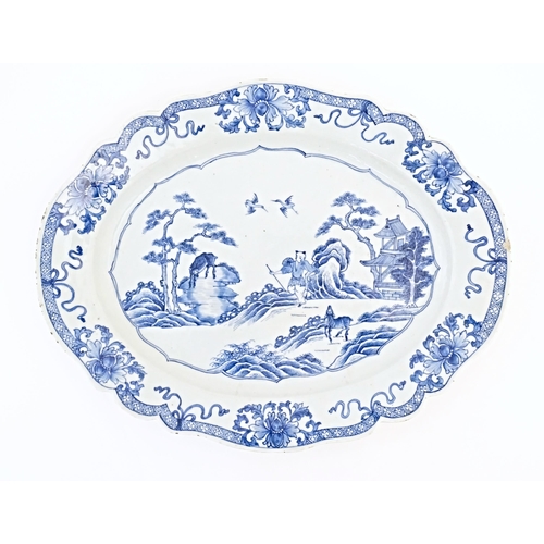 8 - A Chinese blue and white plate of oval form with a shaped rim, decorated with a figure in a rocky la... 