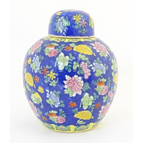52 - A Chinese ginger jar with a blue ground decorated with flowers and foliage. Approx. 10 1/4