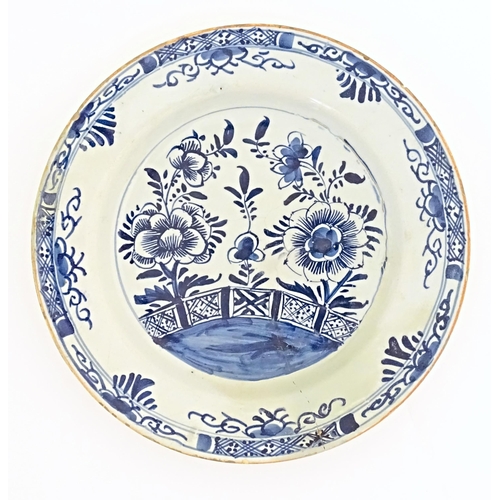 58 - A Delft blue and white plate decorated with flowers and foliage to centre, with a banded border. App... 