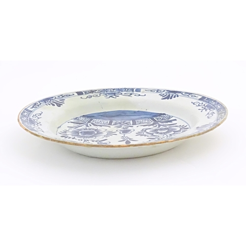 58 - A Delft blue and white plate decorated with flowers and foliage to centre, with a banded border. App... 