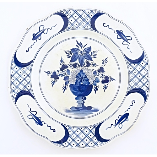 59 - Six blue and white Delft plates decorated with a central bouquet of flowers in a vase, with a patter... 