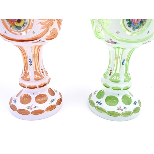 182 - Two Bohemian glass pedestal vases in peach and pale green with white overlay and floral decoration. ... 