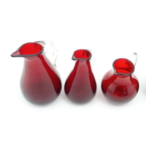 197 - Assorted red glass jugs with clear class handles. To include some Whitefriars examples. The tallest ... 