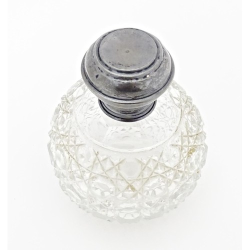 216 - A cut glass scent / perfume bottle with silver top, hallmarked Birmingham 1919. Approx. 3 1/2