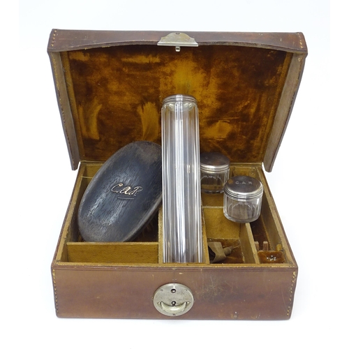 522 - A leather vanity / travelling case  with fitted interior and containing 3 glass bottles with silver ... 