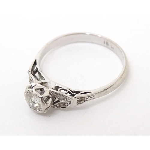 564 - An 18ct white gold ring set with central diamond flanked by further diamonds to shoulders. Ring size... 