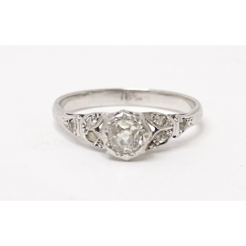 564 - An 18ct white gold ring set with central diamond flanked by further diamonds to shoulders. Ring size... 