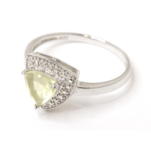 565 - A silver ring set with triangular pale green stone in triangular mount. Ring size approx. M