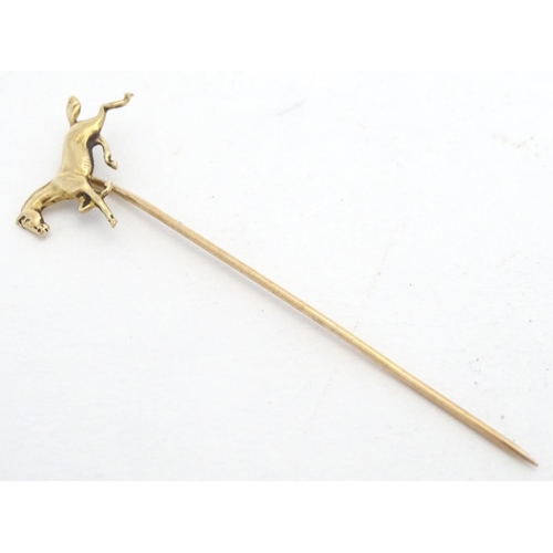 670 - A gold and yellow metal stick pin surmounted by a horse. Marked 10k. Approx 2 3/4