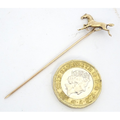 670 - A gold and yellow metal stick pin surmounted by a horse. Marked 10k. Approx 2 3/4