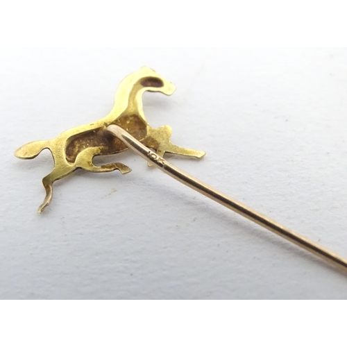 670 - A gold and yellow metal stick pin surmounted by a horse. Marked 10k. Approx 2 3/4