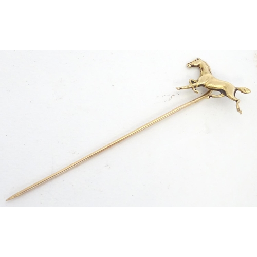 670 - A gold and yellow metal stick pin surmounted by a horse. Marked 10k. Approx 2 3/4