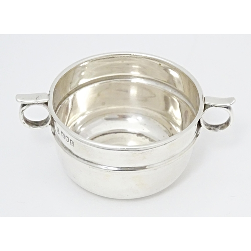 294 - A silver salt formed as a miniature porringer with twin loop handles, hallmarked London 1914, maker ... 