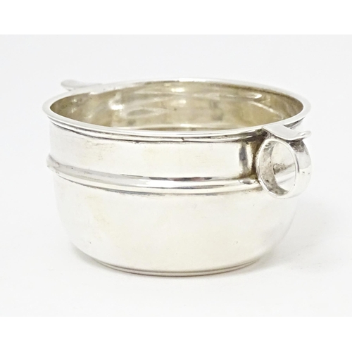 294 - A silver salt formed as a miniature porringer with twin loop handles, hallmarked London 1914, maker ... 