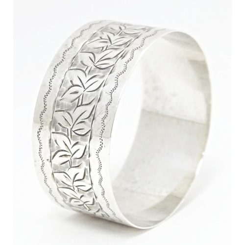 304 - A silver napkin ring with engraved foliate detail, hallmarked Birmingham 1924, maker Henry Williamso... 