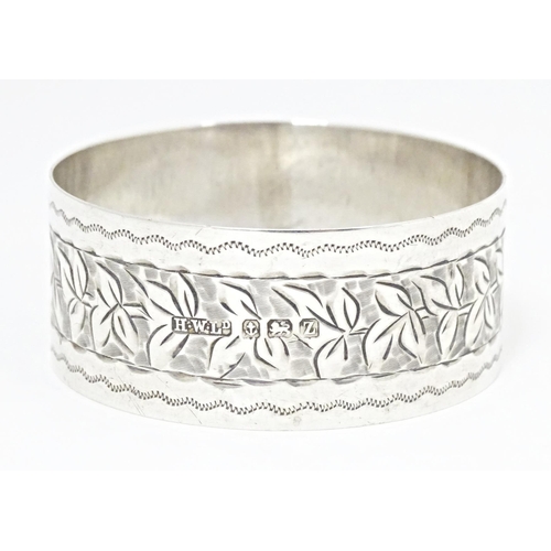 304 - A silver napkin ring with engraved foliate detail, hallmarked Birmingham 1924, maker Henry Williamso... 