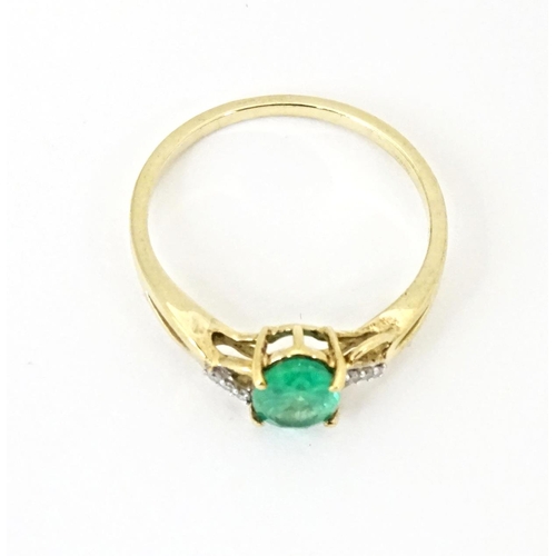 585 - A 9ct gold ring set with central Ethiopian emerald flanked by diamonds. Ring size approx. R