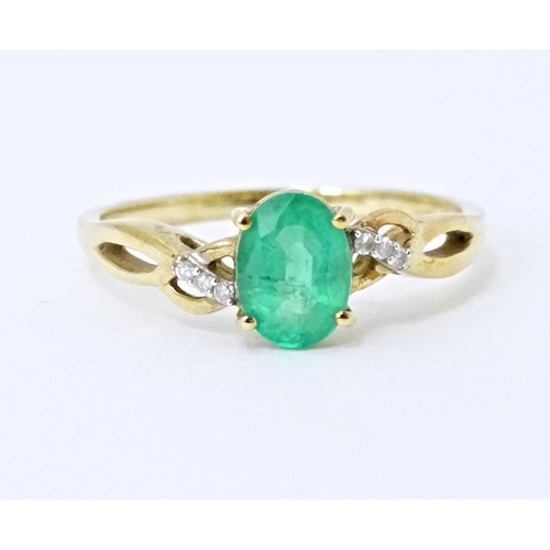 585 - A 9ct gold ring set with central Ethiopian emerald flanked by diamonds. Ring size approx. R