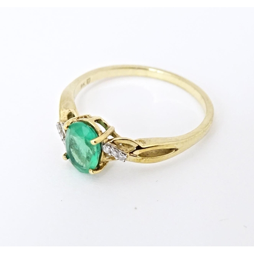 585 - A 9ct gold ring set with central Ethiopian emerald flanked by diamonds. Ring size approx. R