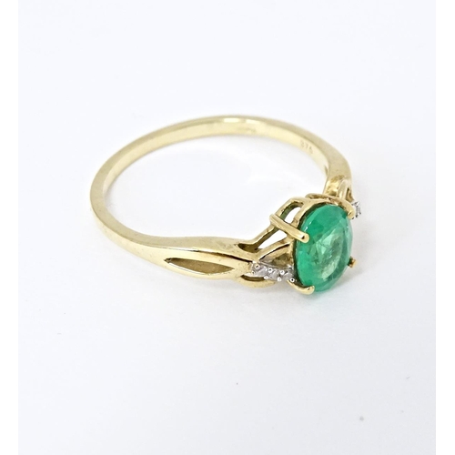 585 - A 9ct gold ring set with central Ethiopian emerald flanked by diamonds. Ring size approx. R