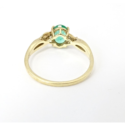 585 - A 9ct gold ring set with central Ethiopian emerald flanked by diamonds. Ring size approx. R