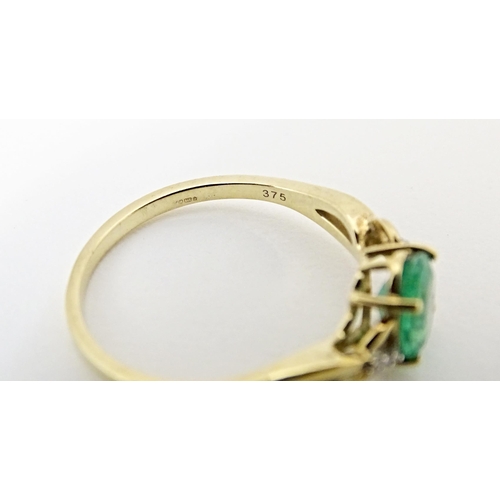 585 - A 9ct gold ring set with central Ethiopian emerald flanked by diamonds. Ring size approx. R