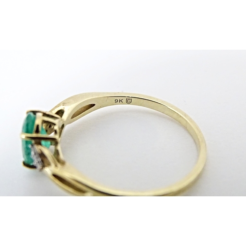 585 - A 9ct gold ring set with central Ethiopian emerald flanked by diamonds. Ring size approx. R