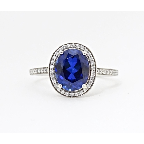 593 - A silver ring set with central blue stone bordered and flanked by cubic zirconia. Ring size approx. ... 