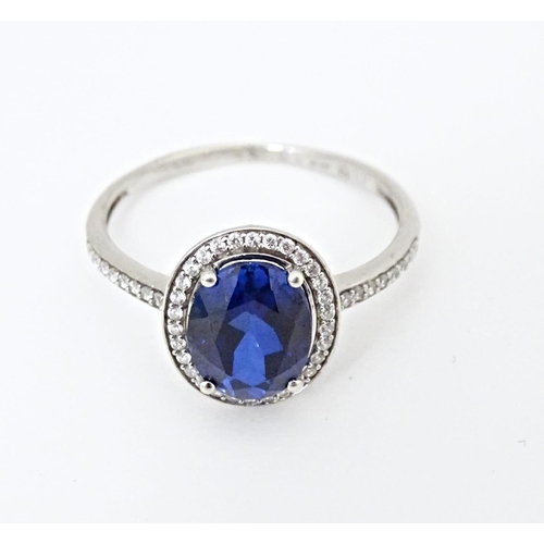 593 - A silver ring set with central blue stone bordered and flanked by cubic zirconia. Ring size approx. ... 