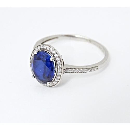 593 - A silver ring set with central blue stone bordered and flanked by cubic zirconia. Ring size approx. ... 