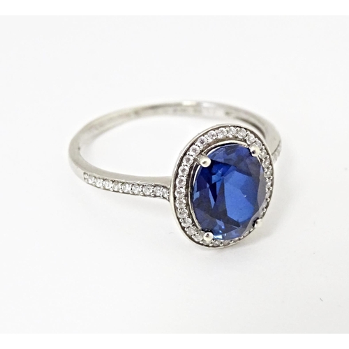 593 - A silver ring set with central blue stone bordered and flanked by cubic zirconia. Ring size approx. ... 