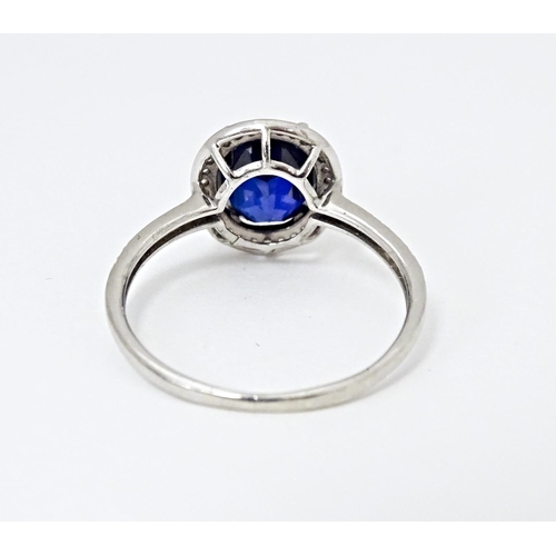 593 - A silver ring set with central blue stone bordered and flanked by cubic zirconia. Ring size approx. ... 