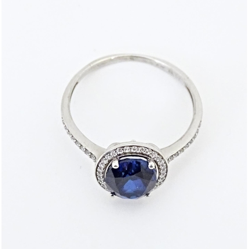 593 - A silver ring set with central blue stone bordered and flanked by cubic zirconia. Ring size approx. ... 