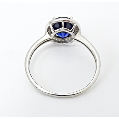 593 - A silver ring set with central blue stone bordered and flanked by cubic zirconia. Ring size approx. ... 