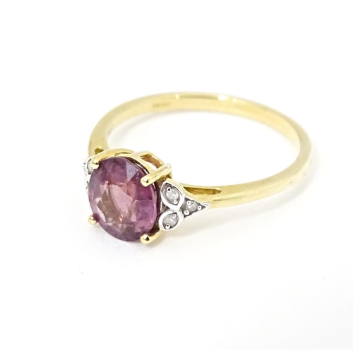 599 - A 9ct gold ring set with central Mangochi garnet flanked by diamonds. Ring size approx. P