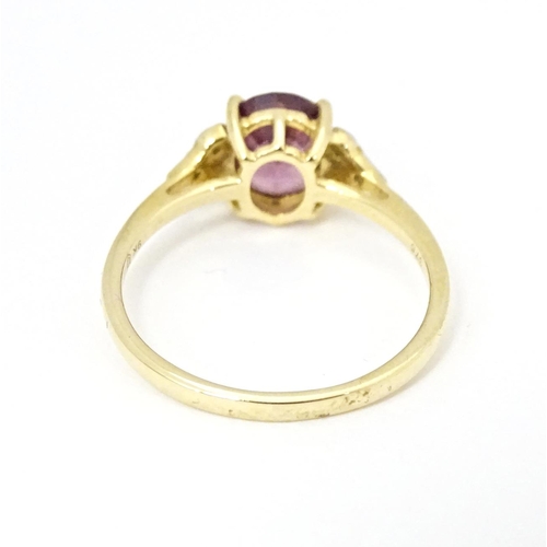 599 - A 9ct gold ring set with central Mangochi garnet flanked by diamonds. Ring size approx. P