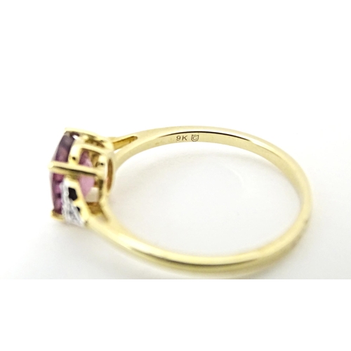 599 - A 9ct gold ring set with central Mangochi garnet flanked by diamonds. Ring size approx. P