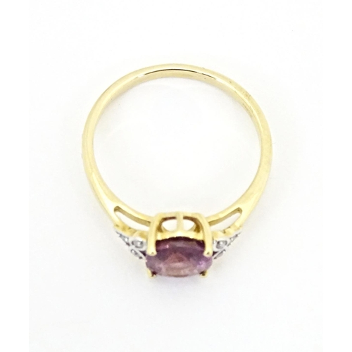 599 - A 9ct gold ring set with central Mangochi garnet flanked by diamonds. Ring size approx. P