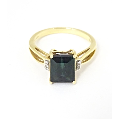 600 - An 18ct gold ring set with central Indicolite tourmaline flanked by diamonds. Ring size approx. M