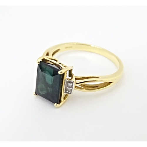 600 - An 18ct gold ring set with central Indicolite tourmaline flanked by diamonds. Ring size approx. M