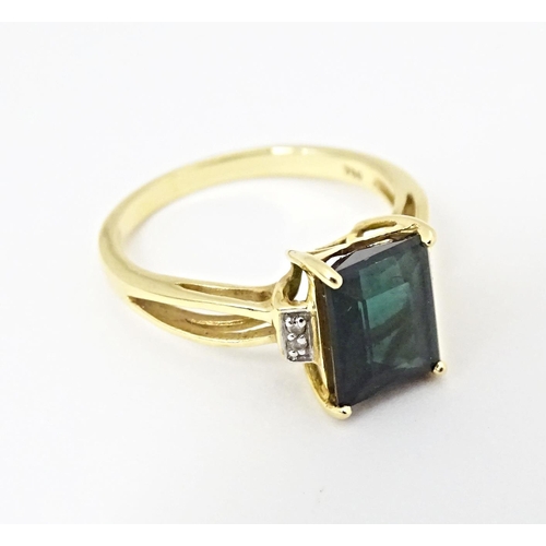 600 - An 18ct gold ring set with central Indicolite tourmaline flanked by diamonds. Ring size approx. M