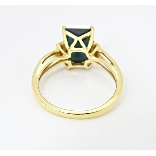 600 - An 18ct gold ring set with central Indicolite tourmaline flanked by diamonds. Ring size approx. M