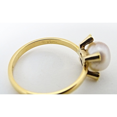 621 - A 22ct gold ring set with central pearl bordered by four diamonds. Ring size approx. S