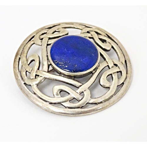 627 - A silver brooch of circular form with Celtic style decoration set central blue cabochon. Approx. 1 3... 