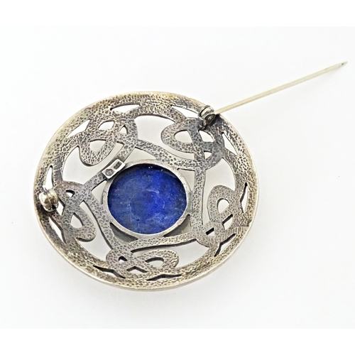 627 - A silver brooch of circular form with Celtic style decoration set central blue cabochon. Approx. 1 3... 