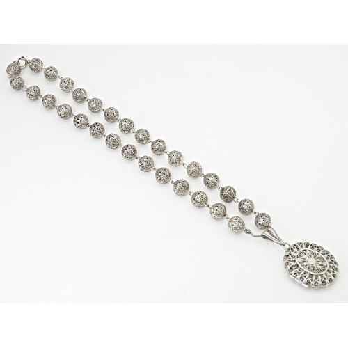 632 - A silver and white metal filigreed bead necklace, with oval filigree pendant locket. Approx. 20