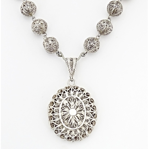 632 - A silver and white metal filigreed bead necklace, with oval filigree pendant locket. Approx. 20