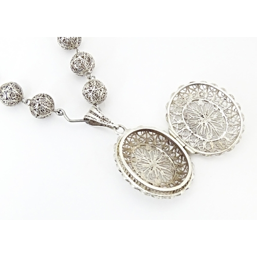 632 - A silver and white metal filigreed bead necklace, with oval filigree pendant locket. Approx. 20