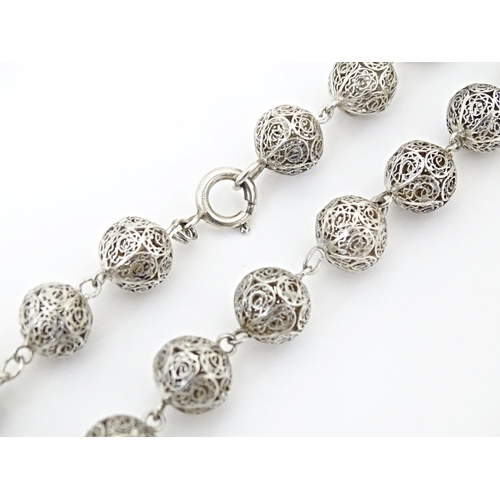 632 - A silver and white metal filigreed bead necklace, with oval filigree pendant locket. Approx. 20