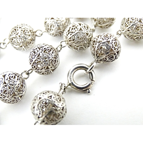 632 - A silver and white metal filigreed bead necklace, with oval filigree pendant locket. Approx. 20